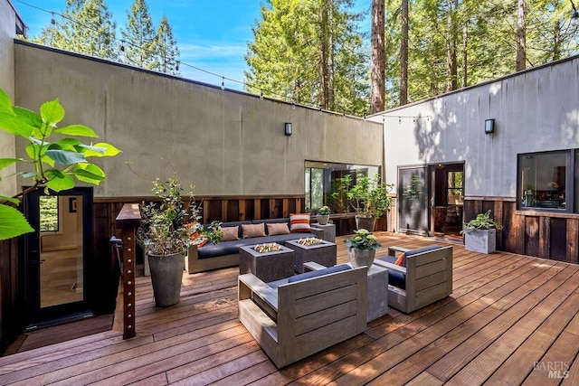 wooden terrace with an outdoor living space with a fire pit