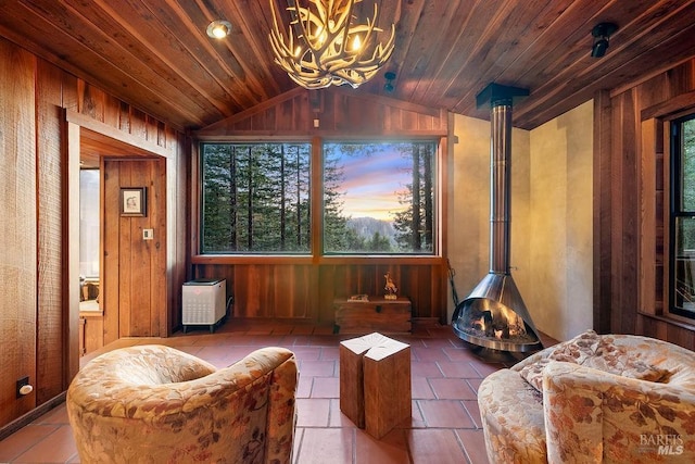 sitting room featuring an inviting chandelier, vaulted ceiling, wooden walls, and a healthy amount of sunlight