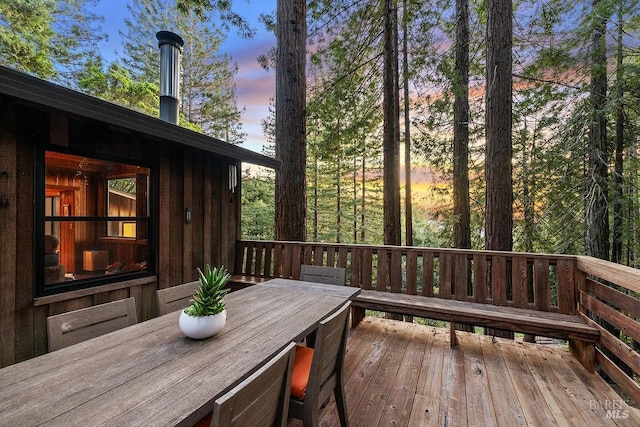 deck at dusk featuring outdoor dining space