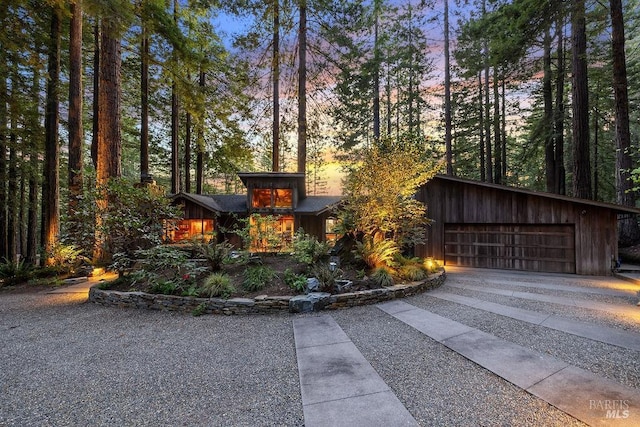 outdoor structure at dusk with driveway and a garage