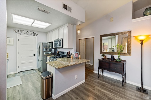kitchen with visible vents, a peninsula, dark wood-type flooring, white cabinets, and appliances with stainless steel finishes