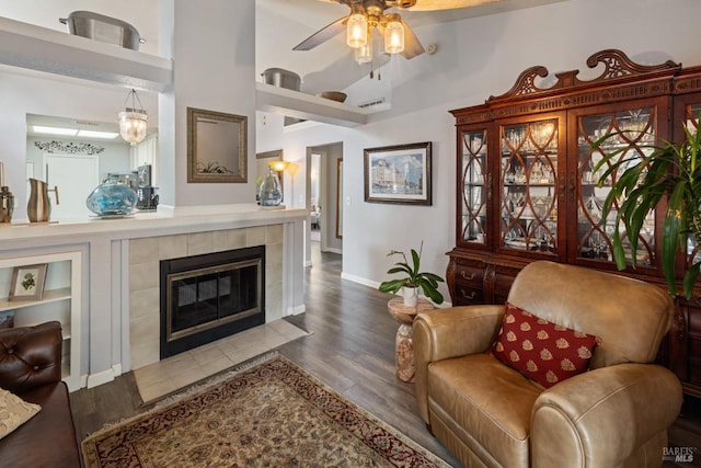 living area with visible vents, wood finished floors, a fireplace, baseboards, and a ceiling fan
