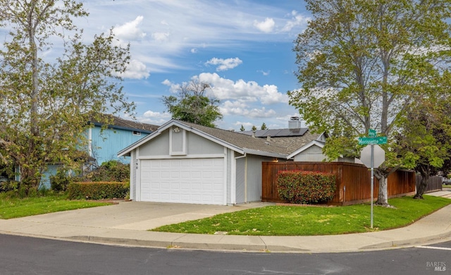 single story home with fence, a front yard, roof mounted solar panels, concrete driveway, and an attached garage