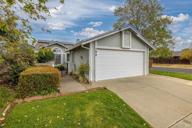 ranch-style house with fence, a garage, stucco siding, roof mounted solar panels, and driveway