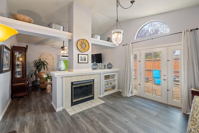 living area with baseboards, high vaulted ceiling, dark wood-style floors, and a tiled fireplace