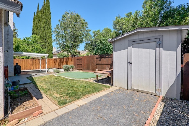 view of yard featuring an area to practice putting, a storage shed, an outdoor structure, and a patio area