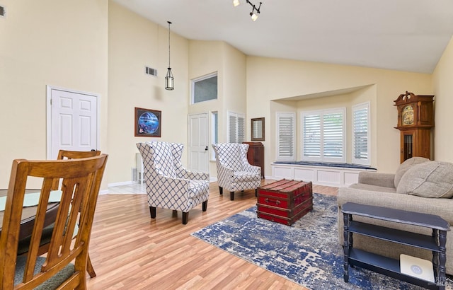 living area featuring light wood-style floors, high vaulted ceiling, and baseboards