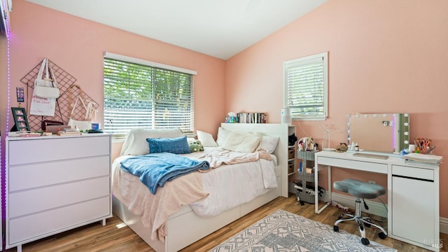 bedroom featuring multiple windows, wood finished floors, and lofted ceiling
