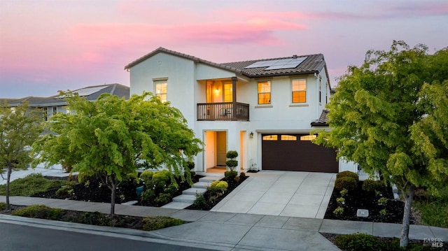 mediterranean / spanish home featuring a tiled roof, solar panels, a balcony, concrete driveway, and stucco siding