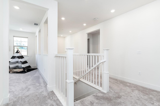 hall with carpet floors, visible vents, recessed lighting, and an upstairs landing