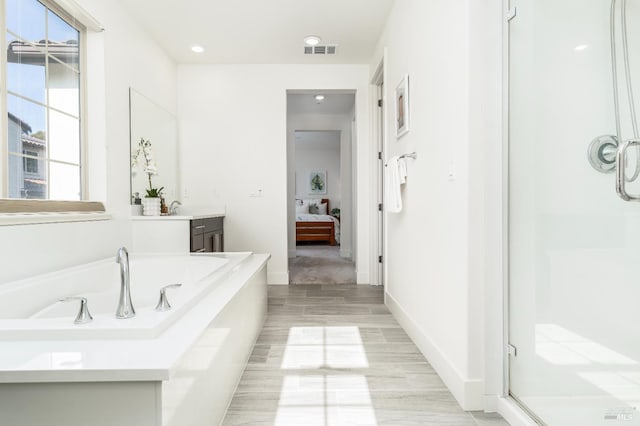 ensuite bathroom with a garden tub, visible vents, a shower stall, wood finished floors, and ensuite bath