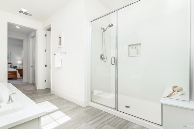 ensuite bathroom featuring visible vents, wood finished floors, baseboards, ensuite bath, and a stall shower