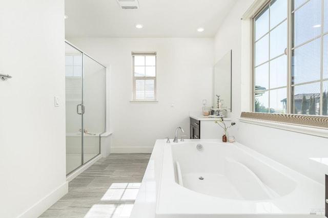 full bathroom with a garden tub, vanity, wood finished floors, baseboards, and a stall shower