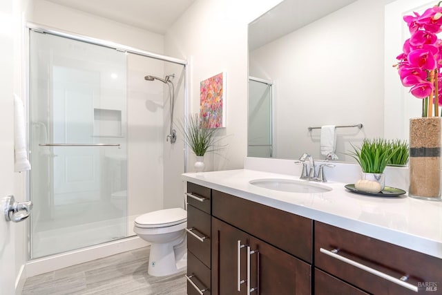 bathroom featuring vanity, a stall shower, toilet, and wood finished floors