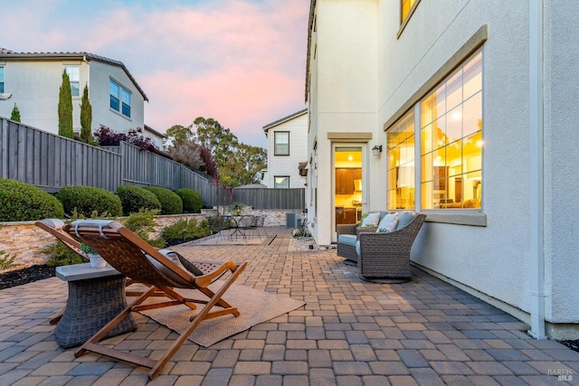 patio terrace at dusk featuring a fenced backyard and central AC