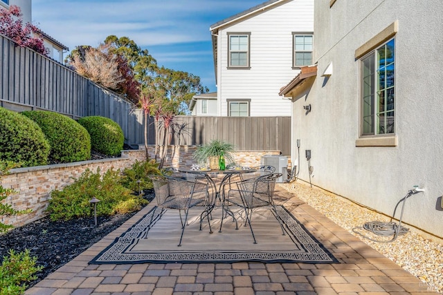 view of patio with outdoor dining area, a fenced backyard, and central AC