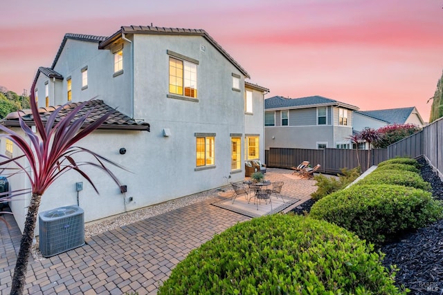 rear view of house with a tile roof, central AC unit, a fenced backyard, and stucco siding