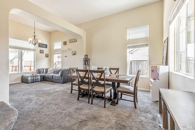 dining area featuring an inviting chandelier, arched walkways, a high ceiling, and carpet flooring
