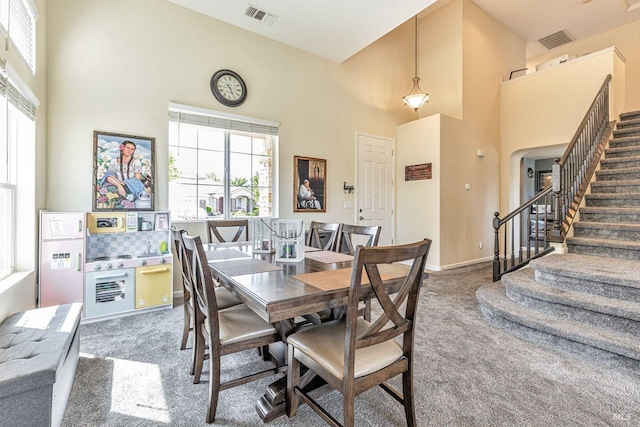 dining space with stairway, a towering ceiling, carpet flooring, and visible vents