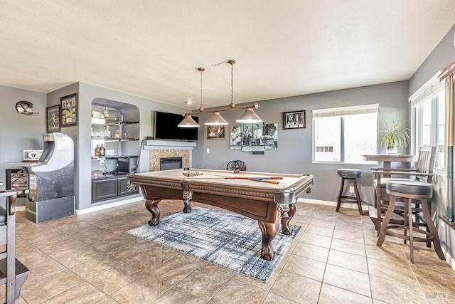 rec room featuring a textured ceiling, pool table, light tile patterned floors, baseboards, and a glass covered fireplace