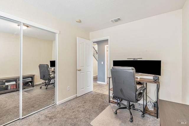 carpeted office space with baseboards and visible vents