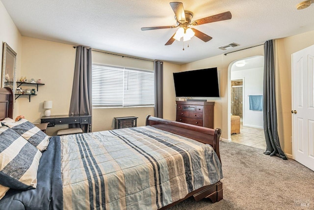 carpeted bedroom with ceiling fan, arched walkways, a textured ceiling, baseboards, and visible vents