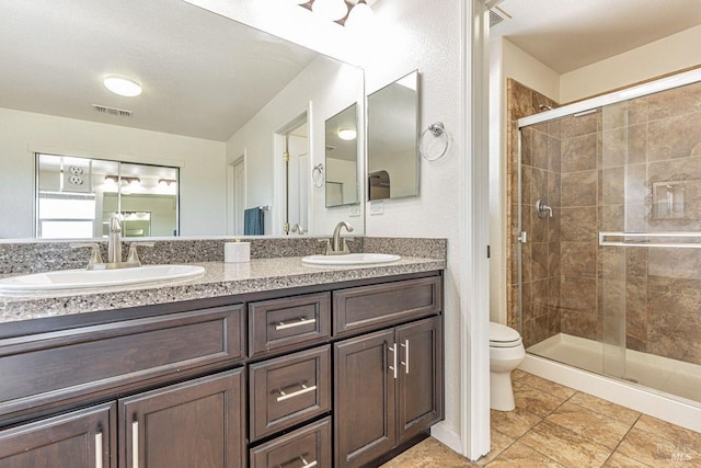 full bath featuring double vanity, toilet, a shower stall, and a sink