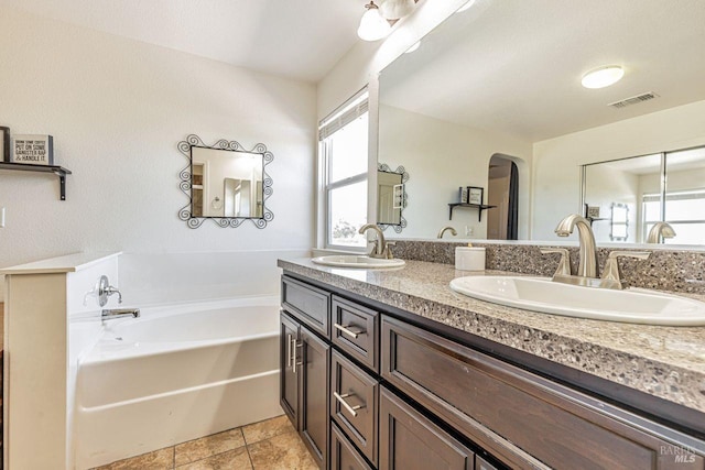bathroom featuring double vanity, visible vents, a sink, and a bath