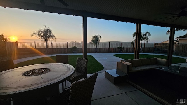 view of patio / terrace featuring a fenced backyard, a ceiling fan, and an outdoor living space with a fire pit