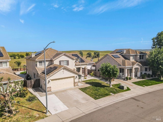 view of front of house featuring concrete driveway, roof mounted solar panels, stucco siding, and fence