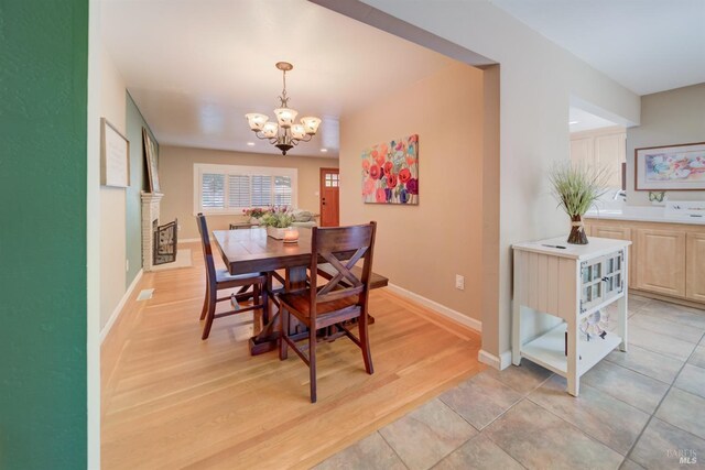 dining space with light wood-style floors, baseboards, recessed lighting, and a notable chandelier