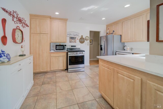 kitchen with light brown cabinetry, appliances with stainless steel finishes, and light countertops