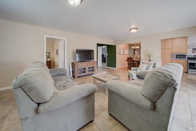living room with baseboards, a notable chandelier, and light tile patterned floors