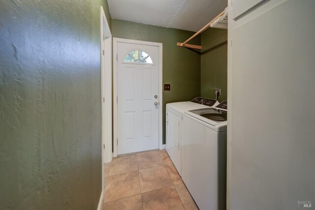 laundry area with laundry area, light tile patterned floors, and washing machine and clothes dryer