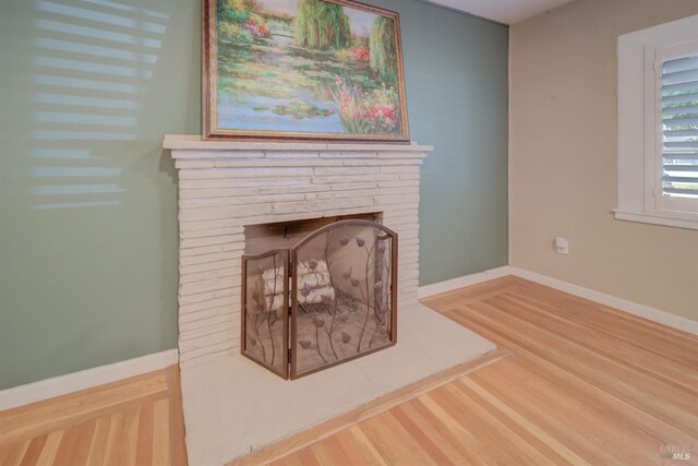 interior details featuring baseboards, a fireplace with raised hearth, and wood finished floors