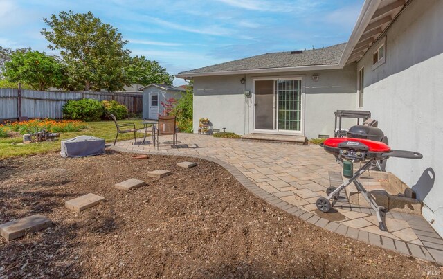 view of patio / terrace featuring a storage unit, fence, and an outbuilding