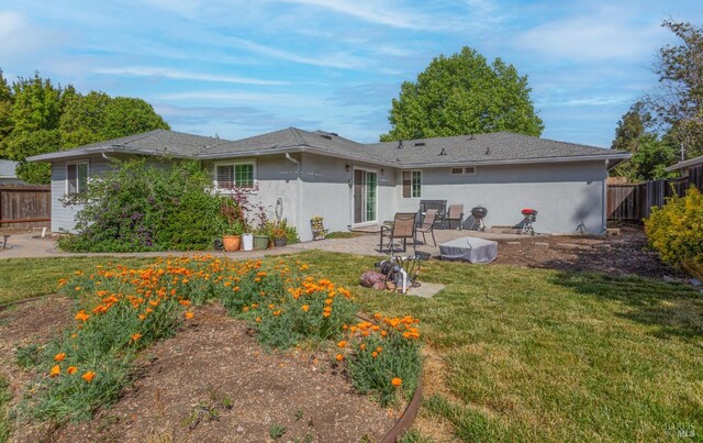 back of house with a lawn, fence, stucco siding, and a patio area