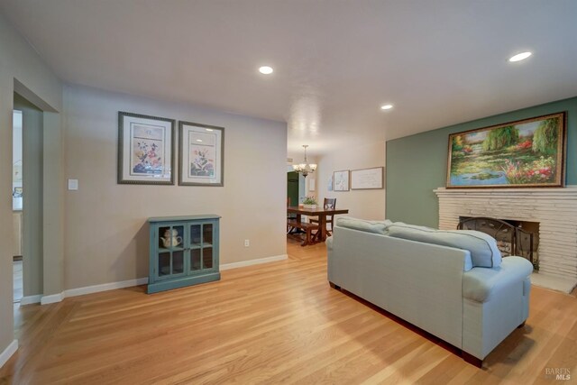 living area with an inviting chandelier, baseboards, and light wood-style floors