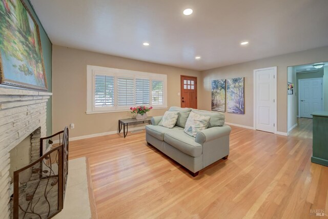 living area with baseboards, a fireplace, recessed lighting, and light wood-style flooring