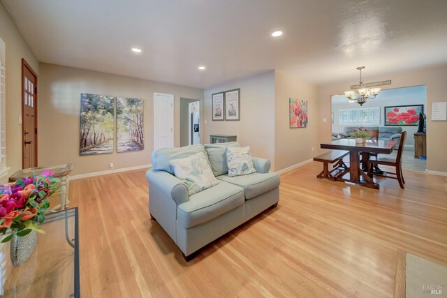 living room with an inviting chandelier, recessed lighting, light wood finished floors, and baseboards