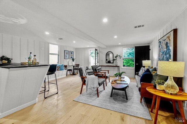 living area with a decorative wall, recessed lighting, visible vents, and light wood-type flooring