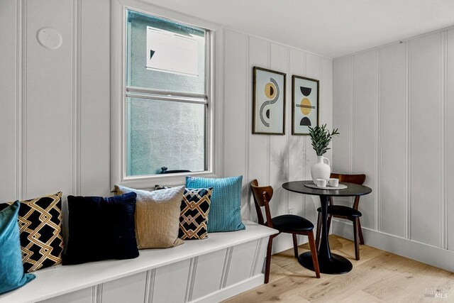 living area with light wood-style floors and a decorative wall