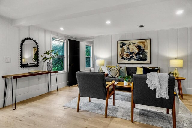 living room featuring wood finished floors, recessed lighting, a decorative wall, and visible vents