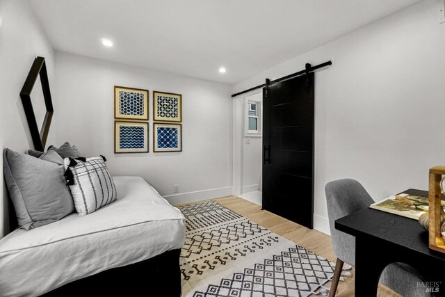bedroom featuring recessed lighting, baseboards, a barn door, and light wood-style floors