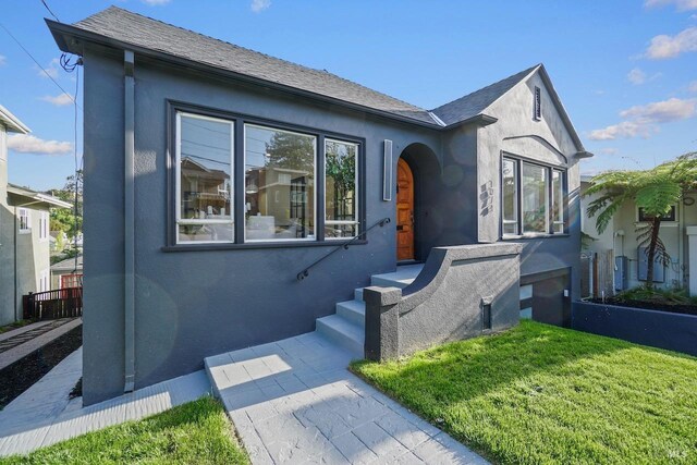 single story home with stucco siding and a front yard