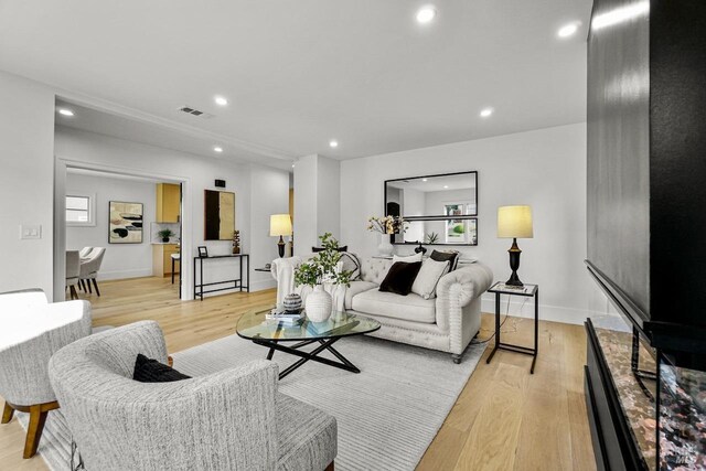 living room with recessed lighting, light wood finished floors, baseboards, and visible vents
