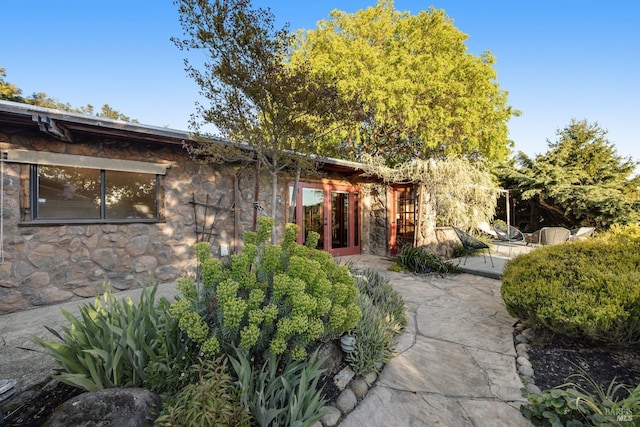 view of front of home featuring a patio, french doors, and stone siding