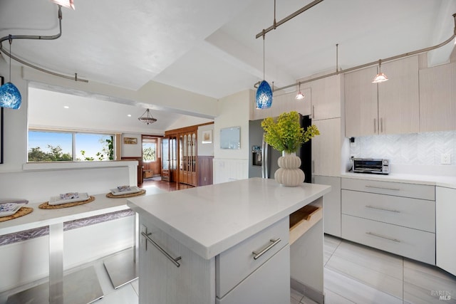 kitchen with stainless steel fridge, light countertops, modern cabinets, and tasteful backsplash