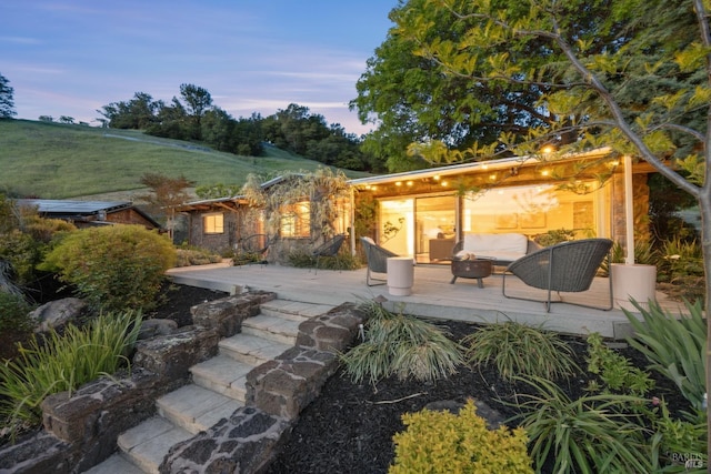 back of property at dusk featuring a deck and a fire pit