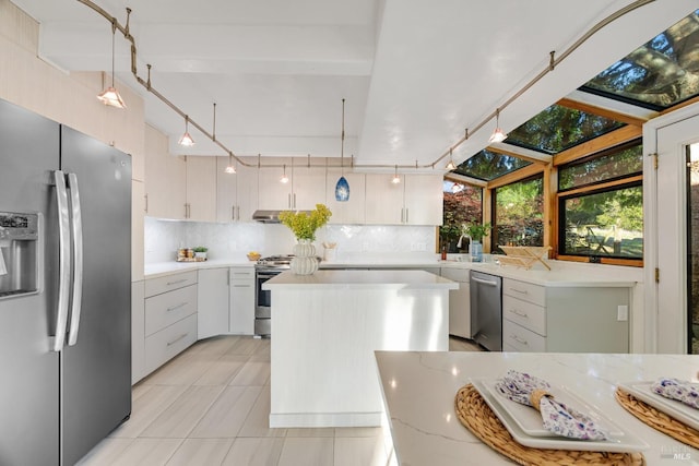 kitchen featuring pendant lighting, a kitchen island, tasteful backsplash, light tile patterned floors, and stainless steel appliances